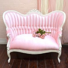 a pink couch sitting on top of a hard wood floor