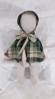 a white doll with a green plaid coat on