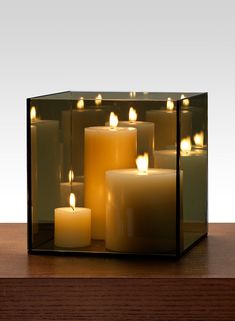 several lit candles in a glass container on a table