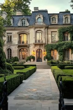 a large house with hedges in front of it and an entry way leading to the entrance