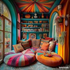 a brightly colored room with an ottoman and bookshelf in the corner is filled with colorful pillows