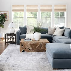 a living room with blue couches and white rugs on the hardwood flooring