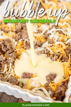 cheese being drizzled over ground beef casserole in a white dish