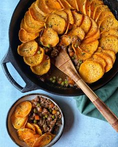 an iron skillet filled with cooked sweet potatoes and peas next to a wooden spoon