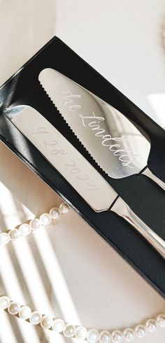 two knives and fork in a black box with pearls on the table next to it