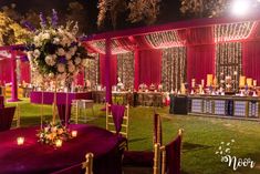 an outdoor event with purple linens and white flowers on the tables, lit up by candles