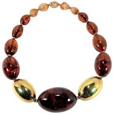 Made in Germany in the late 20th Century, this large 14K Yellow Gold and Baltic Amber ovoid bead necklace makes a strong statement. The largest Amber bead in the center measures 2 1/16 inches long by 1 1/4 inches wide. On either side of the center Amber bead is one large, 14k gold bead measuring 1 11/16 inches long by 1 inch wide. The remaining 12 Amber beads graduate down in size to 7/8 inch long in the back by the clasp. The last four beads adjacent to the clasp are semi baroque Amber beads. Overall length is 22 1/4 inches. The unique 14k gold sliding clasp is marked OBERSTADT 585 and is signed by the artist. There are several photos shown in this listing from various angles, so that you may see the natural characteristics in each Amber bead. Luxury Amber Necklace With Colorful Beads, Luxury Amber Beaded Necklaces With Colorful Beads, Luxury Baltic Amber Necklaces, Luxury Amber Beads Gems And Cabochons, Luxury Large Amber Beads, Luxury Brown Baltic Amber Necklace, Luxury Gold Baltic Amber Necklace, Luxury Bohemian Amber Beads And Cabochons, Luxury Vintage Amber Beads