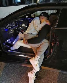 a man sitting in the driver's seat of a car with his feet up