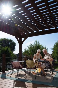 two people sitting on chairs under a pergolated roof