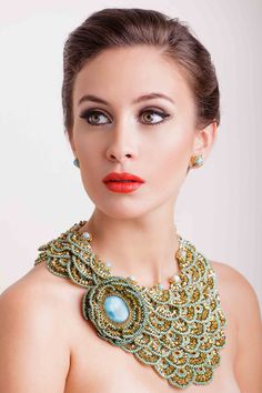 a woman wearing a necklace and earrings with an orange lipstick on her lips, looking at the camera