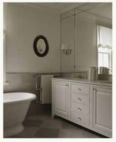 a white bath tub sitting next to a bathroom sink under a mirror on top of a wall