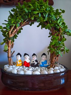 a group of small figurines sitting on top of rocks under a fake tree