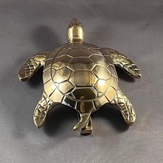 a gold turtle figurine sitting on top of a gray surface with its head turned to the side