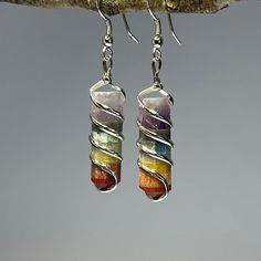 Rainbow Chakra Crystal Earrings, 7 Chakra Gemstone Wire Wrapped Dangle Earrings Item description Stone: Mixed Slice, Amethyst, Jasper, Lapis Lazuli, Aventurine Metal: Wire Wrapped Shape: Rectangle, Point Finish: Polished Length: 40 - 50mm Closure: Ear Wire  Chakra earrings offer a range of metaphysical benefits by harnessing the energy of gemstones and their connection to the body's chakra system. Each gemstone corresponds to a specific chakra, promoting balance, alignment, and healing. These bo Rainbow Dangle Metal Earrings, Multicolor Wire Wrapped Drop Earrings, Multicolor Metal Dangle Crystal Earrings, Rainbow Metal Drop Earrings, Spiritual Multicolor Dangle Earrings, Multicolor Nickel Free Dangle Crystal Earrings, Multicolor Nickel-free Dangle Crystal Earrings, Nickel Free Multicolor Drop Crystal Earrings, Multicolor Spiritual Drop Earrings