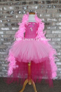 a pink tutule dress on a mannequin stand in front of a brick wall