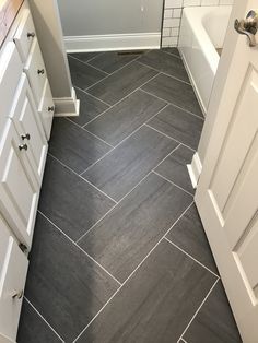 a bathroom with gray and white tile flooring next to a bathtub in the corner