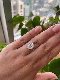 a woman's hand with a diamond ring on her finger, in front of a window