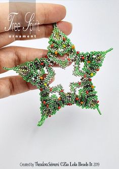 a hand holding a beaded christmas star brooch