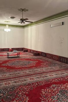 a room with carpet, ceiling fan and table in the middle is empty except for people to see