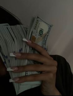 a woman is hiding her face behind stacks of money