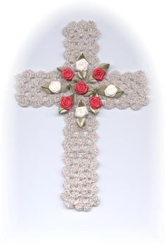 a crocheted cross with red roses and leaves on the center is shown against a white background