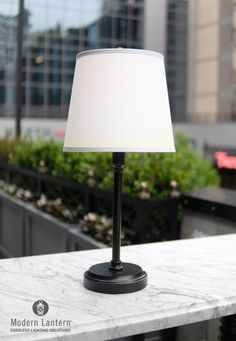 a white lamp sitting on top of a table next to a planter filled with flowers