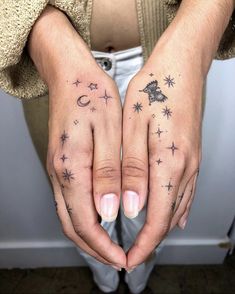 two hands with stars and moon tattoos on them, one is holding the other's hand