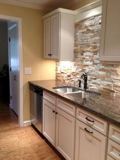 an empty kitchen with white cabinets and granite counter tops, along with wood flooring