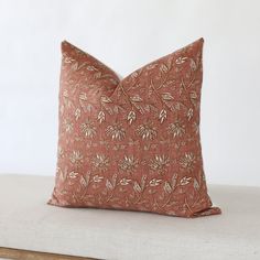 a decorative pillow on a white couch with a brown and tan floral pattern in the middle