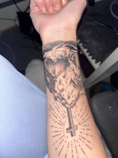 a person with a tattoo on their arm holding a cross