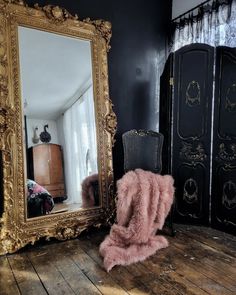 a large mirror sitting on top of a wooden floor next to a chair and dresser