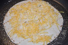 an uncooked tortilla with cheese on it in a skillet pan