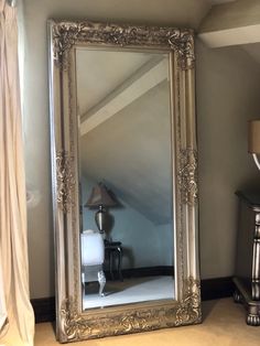 a large silver framed mirror sitting on top of a table next to a night stand