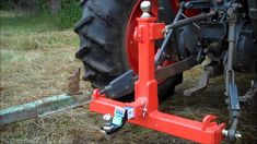 the front end of a red tractor with two wheels on it and one wheel attached