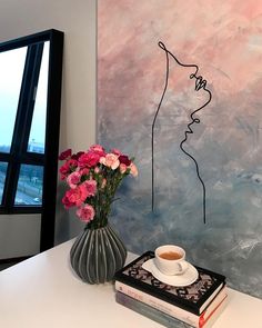 a vase filled with pink flowers sitting on top of a table next to a painting