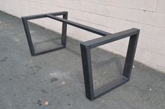 two black frames sitting on the ground next to a brick wall, one is empty