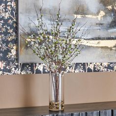 a vase filled with water and flowers on top of a table next to a painting