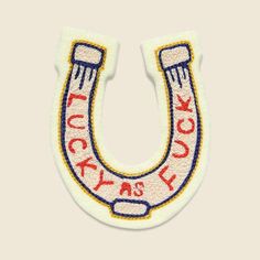 a white and red embroidered horseshoe with the words lucky as luck on it's side