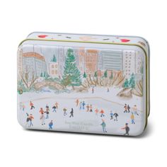 a small tin box with people skating on the ice rink in front of a cityscape