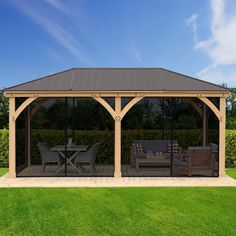 a wooden gazebo sitting on top of a grass covered field next to a table and chairs