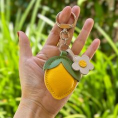 a hand holding a keychain with a flower on it