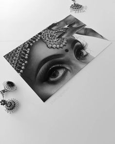 a black and white photo with two pairs of earrings on top of the table next to an image of a woman's face