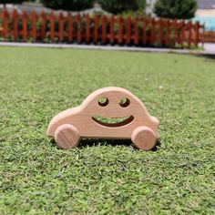 a wooden toy car sitting in the grass with a smiley face on it's side