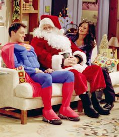 a man dressed as santa claus sitting in a chair with two women