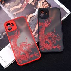 two phone cases sitting on top of a table next to an open magazine and one with a red dragon design