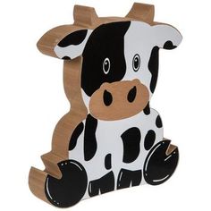 a black and white cow sitting on top of a wooden floor decoration with one eye open