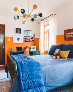 a bedroom with an orange accent wall and blue bedspread on the bottom bed