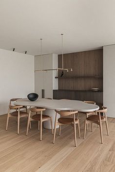 a table and chairs in a room with wood flooring, white walls and wooden floors