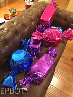 the couch is covered with many different colored foil wrapped presents on it's back