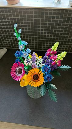 a vase filled with colorful flowers sitting on top of a counter next to a tiled wall